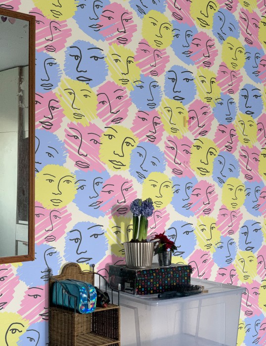 A photo of an interior wall featuring a bright wallpaper with a face pattern
