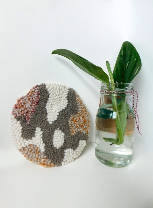 A small tree bark patterned rug photographed next to a plant.